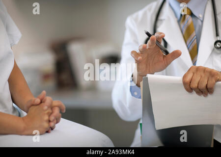 Oberarzt, der nach einer medizinischen Untersuchung mit einem Patienten Rücksprache halten kann Stockfoto