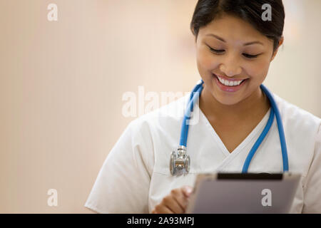 Portrait einer jungen Krankenschwester, die auf einem Klemmbrett schreibt Stockfoto