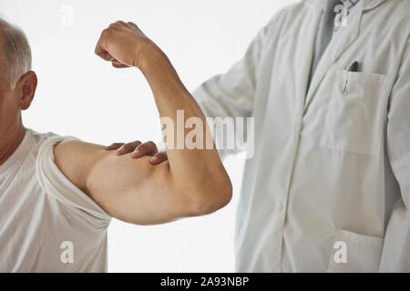 Arzt fühlt den gebeugten Bizepmuskel eines Patienten Stockfoto