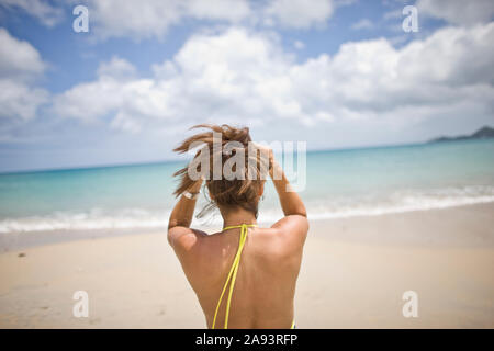 Frau binden bis ihr Haar während am Strand. Stockfoto