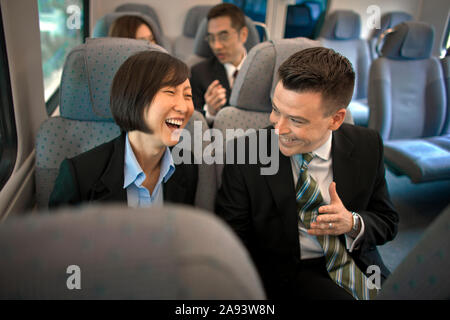 Zwei Geschäftspartnern sprechen und lachen, während der mit dem Zug reist. Stockfoto