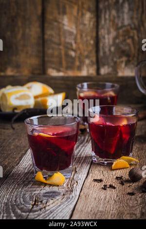 Gläser Weihnachten Glühwein Rotwein mit den Gewürzen und orangen Scheiben auf rustikalen Holztisch. Traditionelle Herbst und Winter warme Getränke