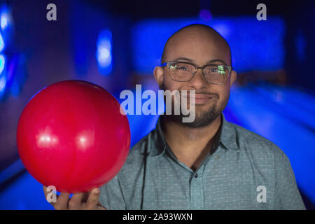 Afroamerikanischer Mann, der Down-Syndrom hält eine Bowling hat Ball Stockfoto