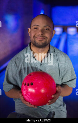 Afroamerikanischer Mann, der Down-Syndrom hält eine Bowling hat Ball Stockfoto