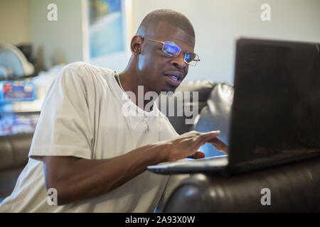 Mann mit Williams-Syndrom, der an einem Computer arbeitet Stockfoto