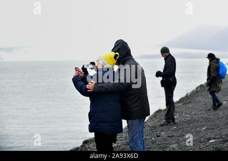 Jökulsárlón, Island. Touristen Pause entlang einer Küste zu sehen und fotografieren Eisberge vom Gletscher Vatnajökull schweben frei im See. Stockfoto