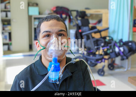 Junge mit spastischen viereckigen Zerebralparese Lernen in der Schule und Mit seiner medizinischen Atemmaske Stockfoto