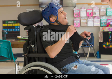 Junge mit spastischen viereckigen zerebralen Lähmung mit Verwendung seiner speziellen Braucht Helm Stockfoto