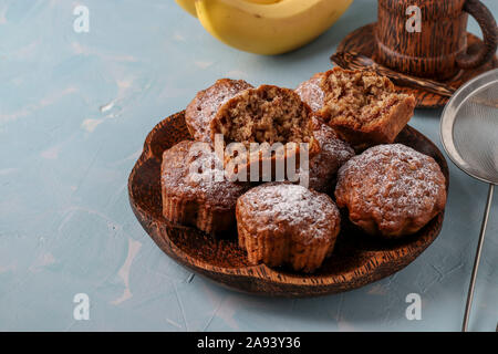 Banana Muffins mit Haferflocken Flocken bestreut mit Puderzucker auf eine Kokosnuss Platte, horizontale Ausrichtung Stockfoto