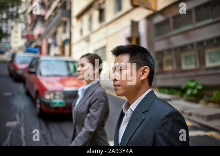 Zwei junge Kollegen zu Fuß entlang einer belebten Straße. Stockfoto