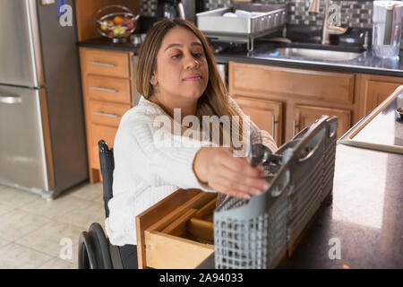 Frau mit Rückenmark Verletzung Anordnung Geschirrspüler Stockfoto