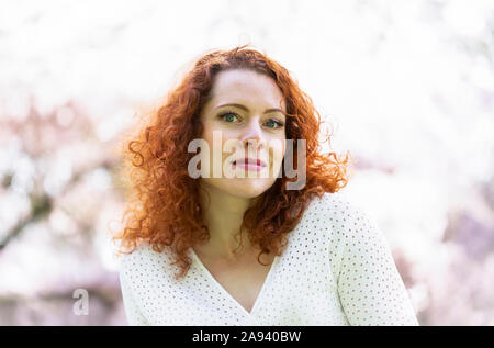 Porträt einer Frau mit roten Haaren zwischen den Kirschblüten; Vancouver, British Columbia, Kanada Stockfoto