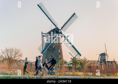 Kinderdijk, Niederlande - 20 April, 2019: Touristen vorbei Wind Mill in Kinderdijk bei Sonnenuntergang in der Nähe von Rotterdam Stockfoto