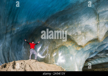 Ein Mann posiert in einer Eishöhle des Castner Glacier; Alaska, Vereinigte Staaten von Amerika Stockfoto