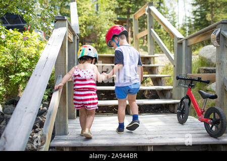 Bruder Hände mit Schwester, der ihr hilft, Holztreppe. Stockfoto