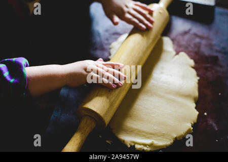 Ein Kind rollt den Teig cookies zu machen. Stockfoto