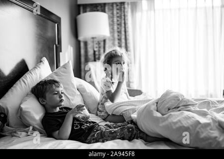 Zwei Kinder liegen in einem Hotel Zimmer Bett Snacks essen. Stockfoto