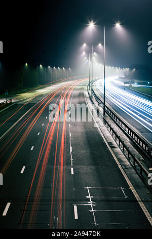 Ampel Trails. Lange Belichtung eines britischen Autobahn bei Nacht mit Verkehr Trails, die Autos fahren auf der linken Seite. Stockfoto
