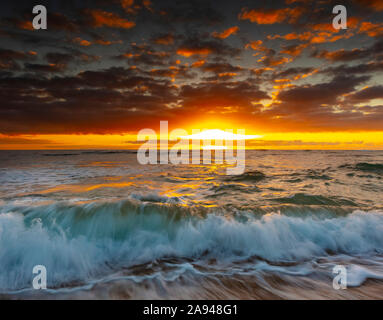 Heller, goldener Sonnenaufgang über Strand und Meer; Kauai, Hawaii, Vereinigte Staaten von Amerika Stockfoto