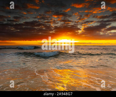 Heller, goldener Sonnenaufgang über Strand und Meer; Kauai, Hawaii, Vereinigte Staaten von Amerika Stockfoto