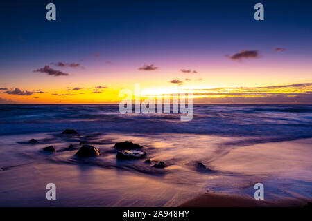 Heller, goldener Sonnenaufgang über Strand und Meer; Kauai, Hawaii, Vereinigte Staaten von Amerika Stockfoto