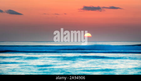 Sinkende Sonne über dem Horizont des Ozeans mit weichen Wellen; Kauai, Hawaii, Vereinigte Staaten von Amerika Stockfoto