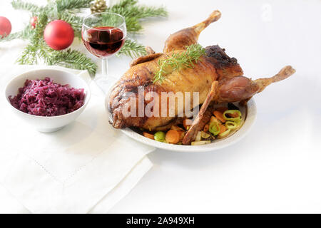 Gebratene ganze Ente mit Gemüse, Rotkohl und Wein auf einem weißen Tisch mit Weihnachtsdekoration, Kopie, ausgewählte konzentrieren Stockfoto