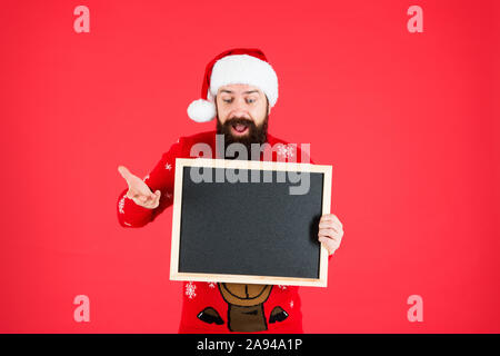 Unglaublich. Santa Claus hat mit Werbung. Schwarzes Brett für Informationen. Mann leere Tafel kopieren. Guy santa claus roten Hintergrund. Winter Ankündigung. Winter event. Winterurlaub. Stockfoto