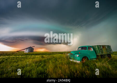 Oldtimer-LKW auf Ackerland unter einem dramatischen stürmischen Himmel; Moose Jaw, Saskatchewan, Kanada Stockfoto