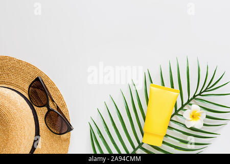 Blick von oben auf die Sonnencreme, Strohhut, Palmblatt, Sonnenbrille.spf Creme auf weißem Hintergrund mit kopieren. Direkt oberhalb. Helle Sommer, Ferien Stockfoto