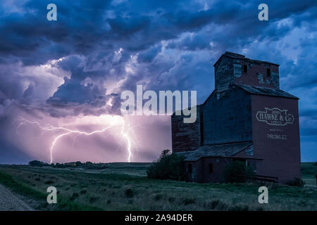 Getreideaufzug in einem dramatischen Gewitter mit dunklen Wolken und Blitzeinschlägen in der Ferne; Saskatchewan, Kanada Stockfoto