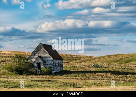 Alte, verlassene Landkirche verwittert aus den Jahren auf den Prärien und ein Oldtimer links im Feld hinter; Val Marie, Saskatchewan, Kanada Stockfoto