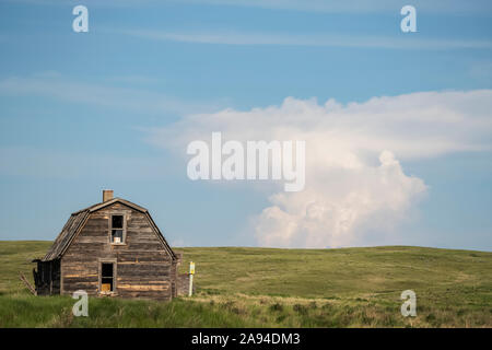 Verlassene Scheune auf Ackerland mit einzigartiger Wolkenformation in der Ferne; Val Marie, Saskatchewan, Kanada Stockfoto