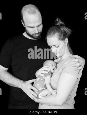 Porträt eines neugeborenen Babys, das in den Armen der Mutter schläft, während der Vater in einer Umarmung steht; Vancouver, British Columbia, Kanada Stockfoto