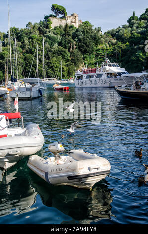 Italien, Portofino - 3. Oktober 2014: Boote auf dem Wasser in der malerischen Bucht von Portofino mit Blick auf die bunten Häuser Stockfoto