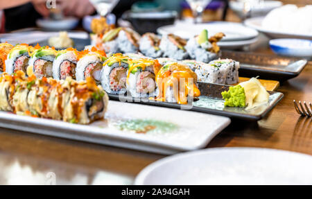 Platten mit verschiedenen Arten von fachmännisch zubereitet und in Scheiben geschnittenen Sushi mit Gewürzen und Saucen sind auf Esstisch köstlich und diätetische zu genießen angezeigt Stockfoto