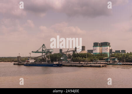 Lange Tau Fluss, Vietnam - 12. März 2019: Nhon Trach. INSEE Zement station mit Silos, Förderbänder, und seine Quay, wo Tuan Minh Boot ist entladen Stockfoto