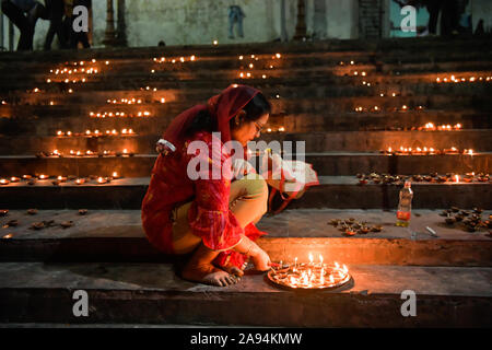 Kolkata, Indien. 12 Nov, 2019. Eine Frau, die Beleuchtung ein Fach voll von irdenen Lampen das Ritual auf Dev Deepawali. Dev Deepawali ist auf den Tag des Vollmondes beobachtet (Purnima) im Monat Kartik nach vierzehn Tagen von Diwali. Credit: SOPA Images Limited/Alamy leben Nachrichten Stockfoto