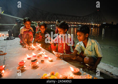 Kolkata, Indien. 12 Nov, 2019. Kinder, die die Schritte der Ghat der Ganges, der mit irdenen Lampen während Dev deepawali dekoriert ist. Dev Deepawali ist auf den Tag des Vollmondes beobachtet (Purnima) im Monat Kartik nach vierzehn Tagen von Diwali. Credit: SOPA Images Limited/Alamy leben Nachrichten Stockfoto