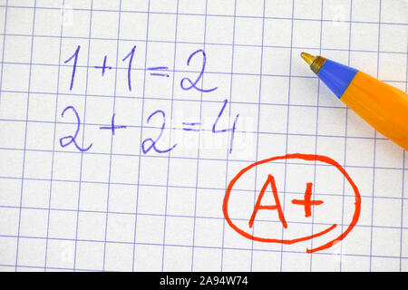 Ein Plus (A+) Grad auf Notebook Blatt Papier mit mathematischen Operation gelöst. Close Up. Stockfoto