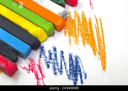 Anschläge von Pastellkreiden und Stifte in verschiedenen Farben auf einem weißen Blatt Papier Stockfoto