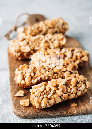 Hausgemachte eclairs mit peanut auf Schneidebrett. Nahaufnahme der leckeren, gesunden profitroles mit Muttern. Kopieren Sie Platz für Text oder Design. Vertikale. Stockfoto