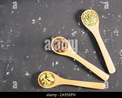 Drei Löffel mit Gewürze auf einem konkreten Hintergrund schwarz-grünen Kardamom, Fenchel, Piment. Indische Küche Zutaten Stockfoto