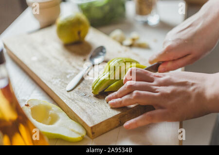 Schneiden Birnen in einem Salat auf einem Holzbrett - selbstgemachtes Rezept - der hausfrau Hände - Ländliche Stockfoto