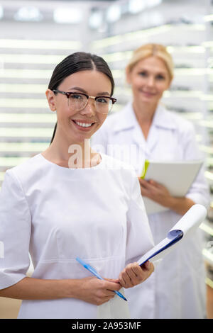 Assistant gutes Gefühl. Fröhlicher Assistent von Auge Doktor Brille gut fühlen, während sie mit der Arbeit beginnen Stockfoto
