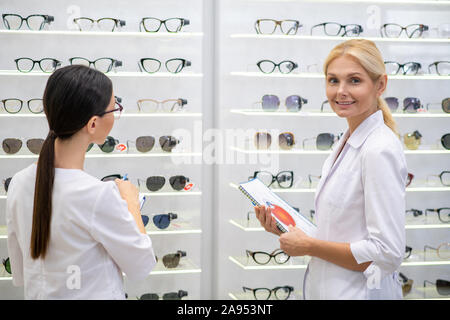 In der optischen Speichern. Zwei Augenärzte tragen weiße Mäntel arbeiten hart, beim Stehen in der optischen Speichern Stockfoto