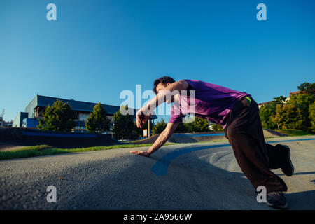 Junge akrobatische Kerl, Parkour Workout an der Skate Spielplatz Stockfoto