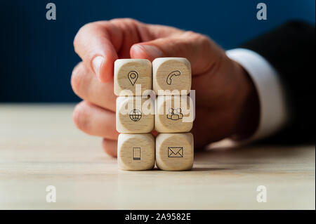 Geschäftsmann stapeln Holz- Würfel mit Symbolen den Kontakt und die Informationen über Sie in einem konzeptionellen Bild von Business Support und Service. Stockfoto