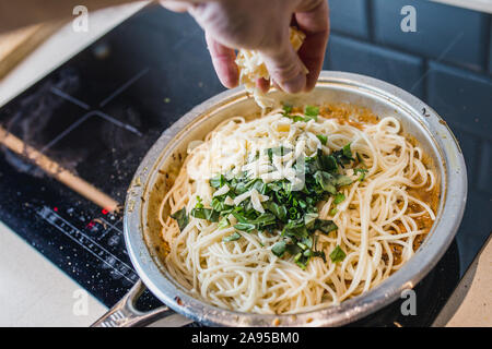 Spaghetti Pasta in einer cremigen Sauce in einer Pfanne mit gehacktem Basilikum, Käse und Gewürze - Kochen zu Hause Stockfoto