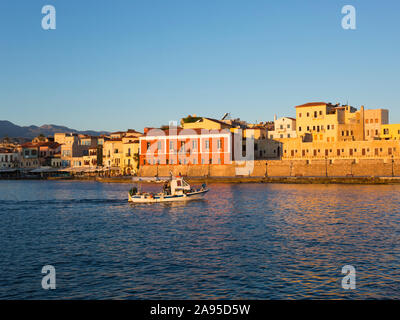 Chania, Kreta, Griechenland. Blick über den venezianischen Hafen bei Sonnenaufgang, Fischerboot auf dem Weg zum Meer. Stockfoto